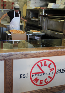Photo by Shelby Townsend A worker at the Villa Meci Pizzeria in Glen Cove removes a fresh pizza from the oven