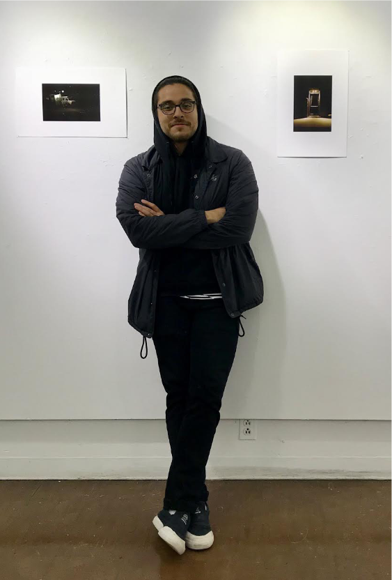 Jeffrey Gomez leans against the gallery walls of his photo exhibit